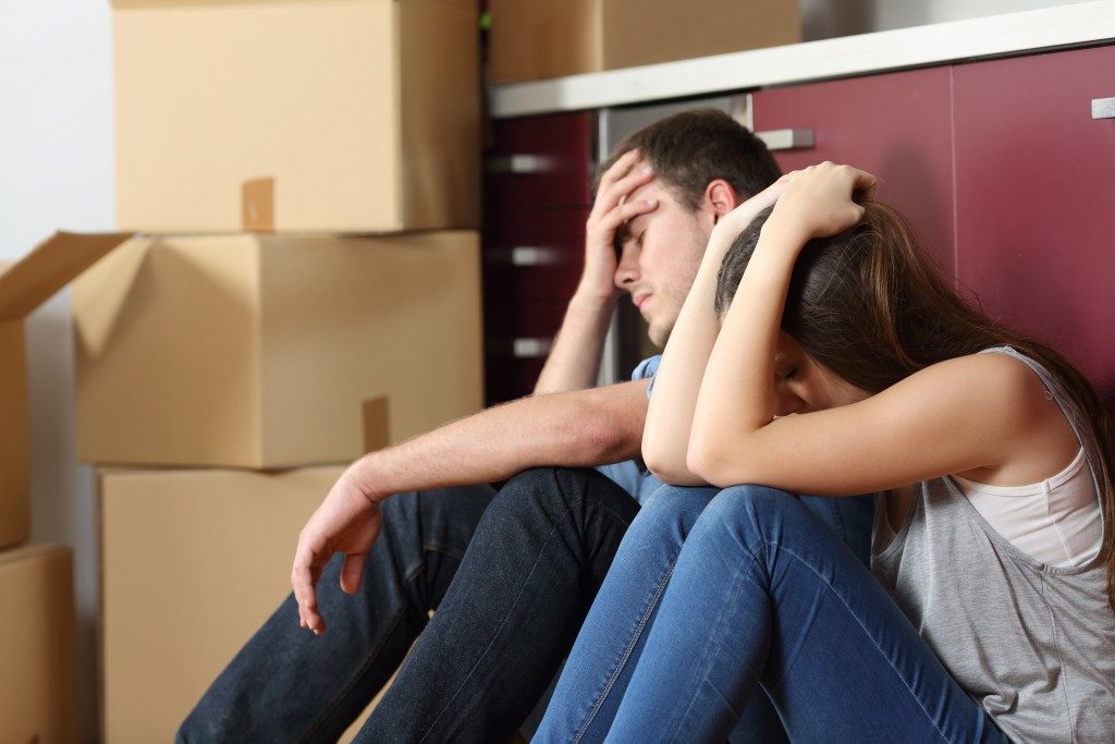 Angry evicted couple worried and sitting on the floor with hand on head