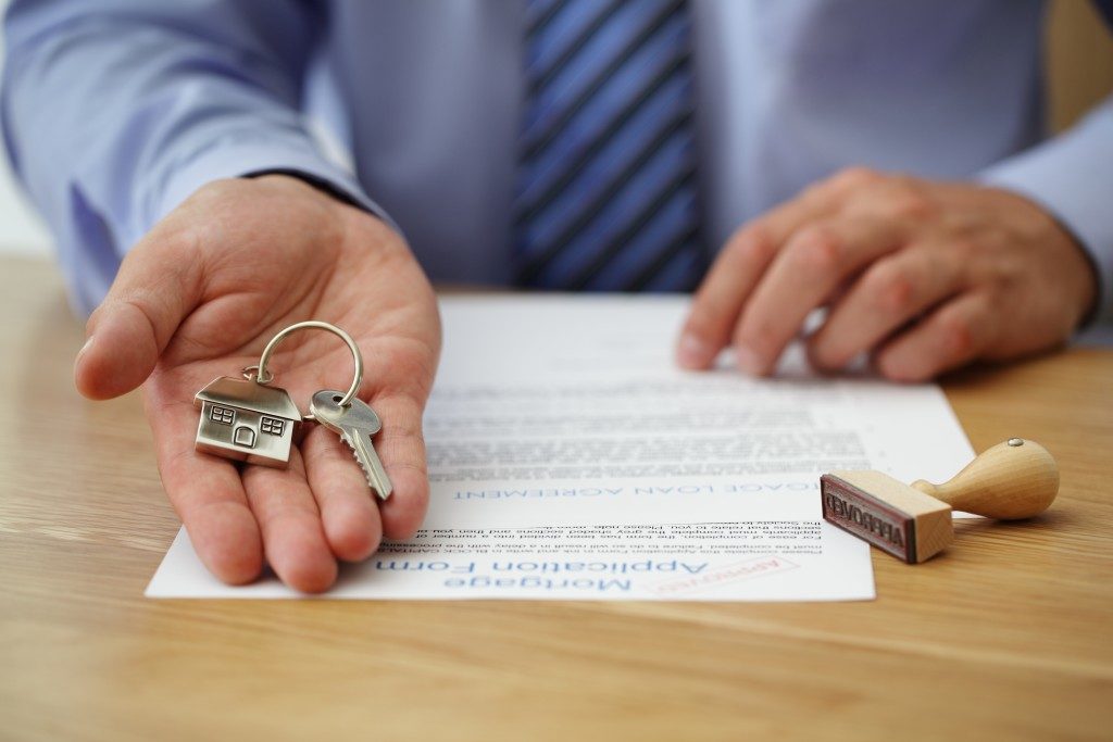 real estate agent handling house key with approved mortgage application