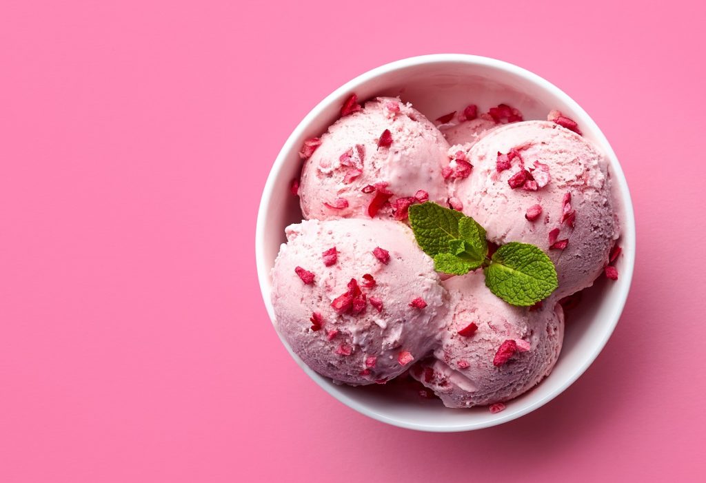 Strawberry ice cream in bowl with pink background