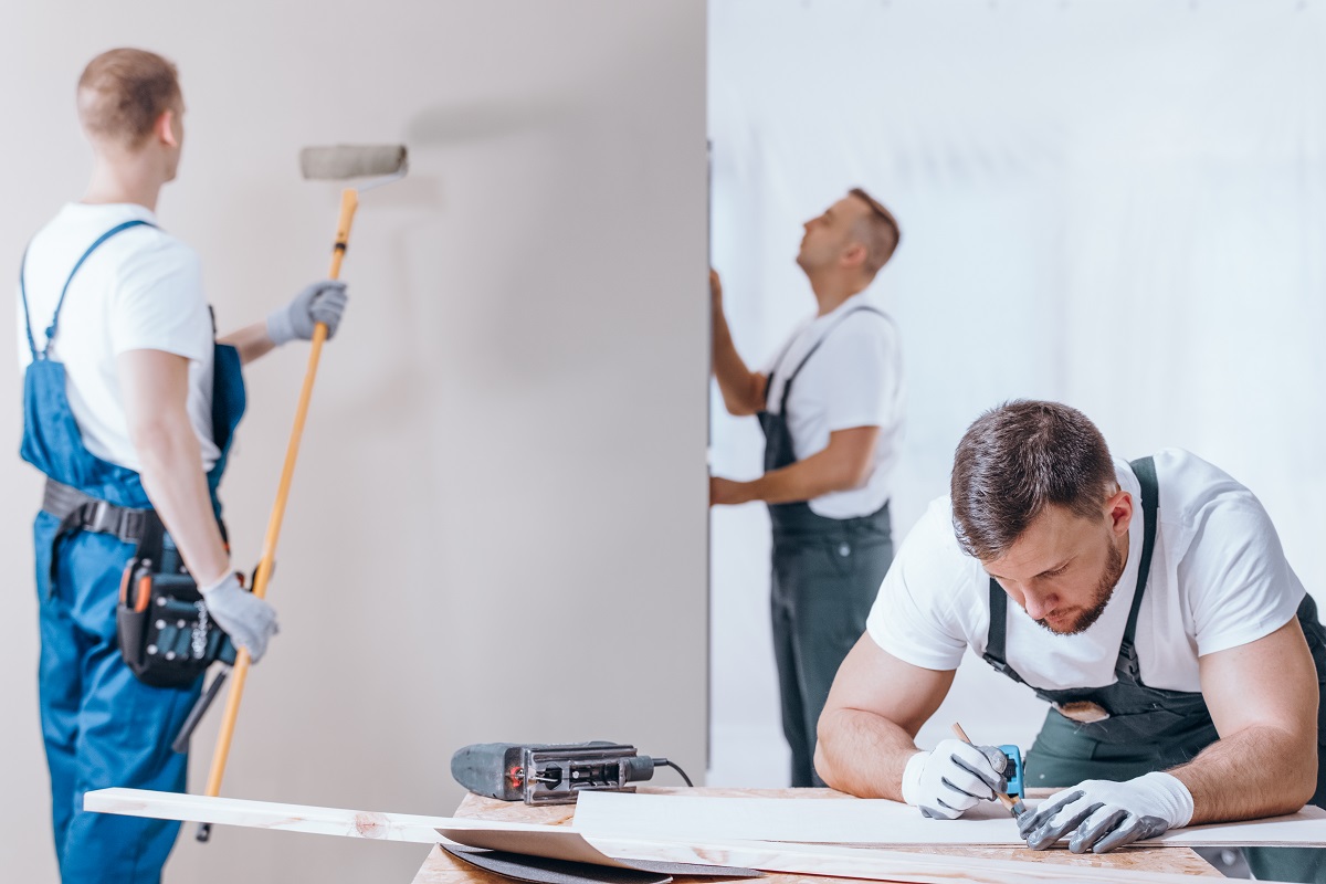 male workers in overalls painting and building in a home remodel project