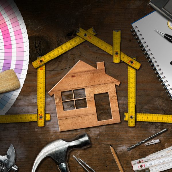 Home renovation tools surrounding a wooden cutout of a house