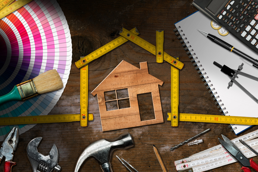 Home renovation tools surrounding a wooden cutout of a house