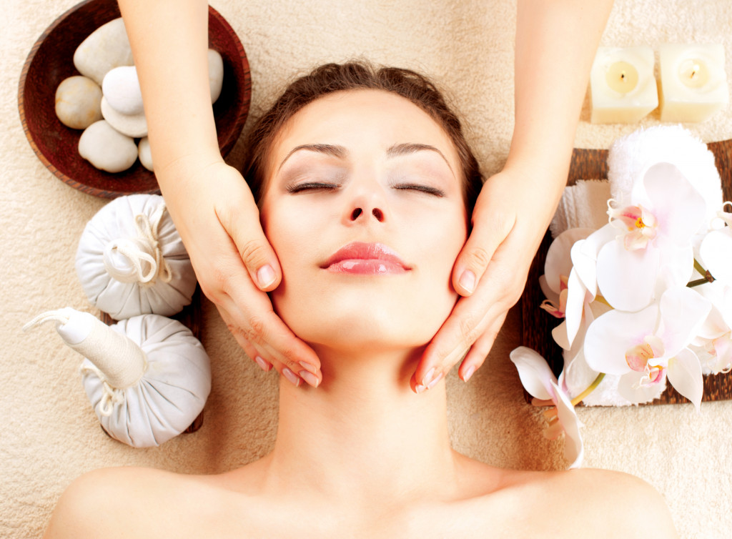 woman smiling with eyes closed while having a facial massage at a spa