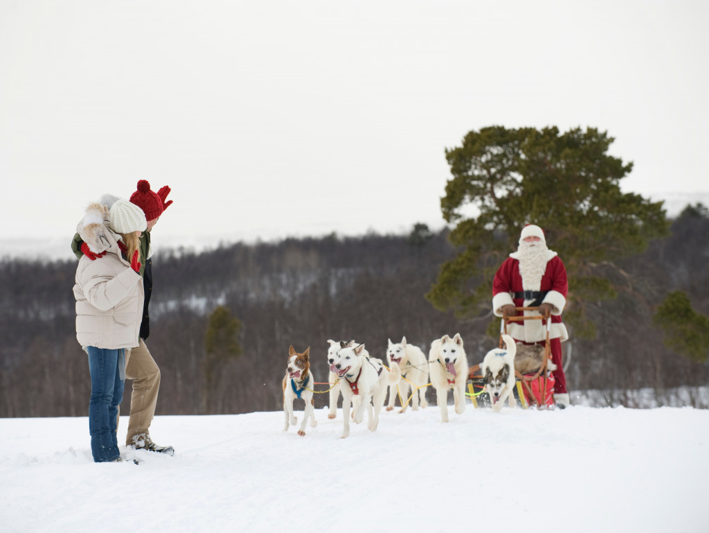 santa arriving on a dog sled with couple waiting