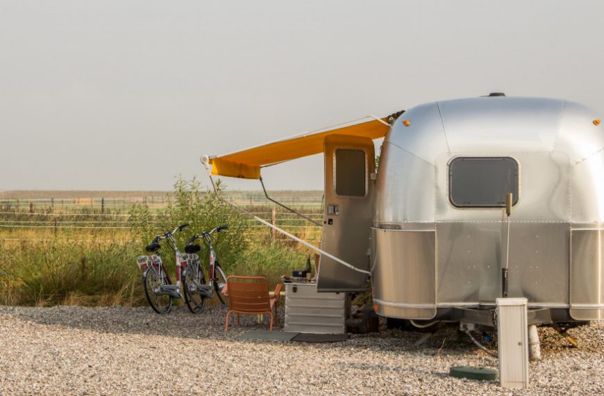 a mobile home parked in a farm with bikes outside and seating area