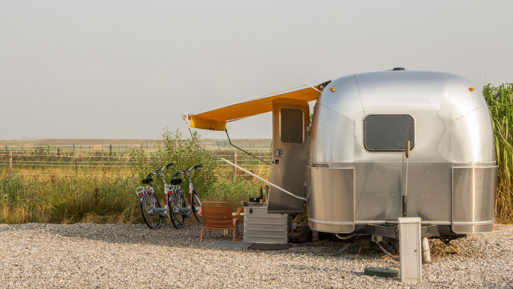 a mobile home parked in a farm with bikes outside and seating area