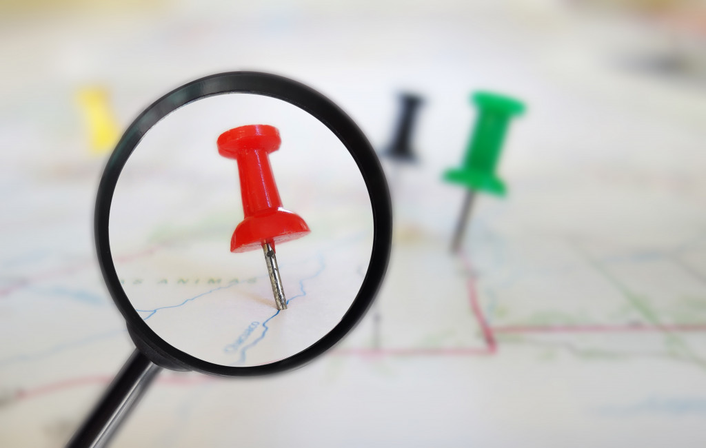 red push pin under a magnifying glass representing a location