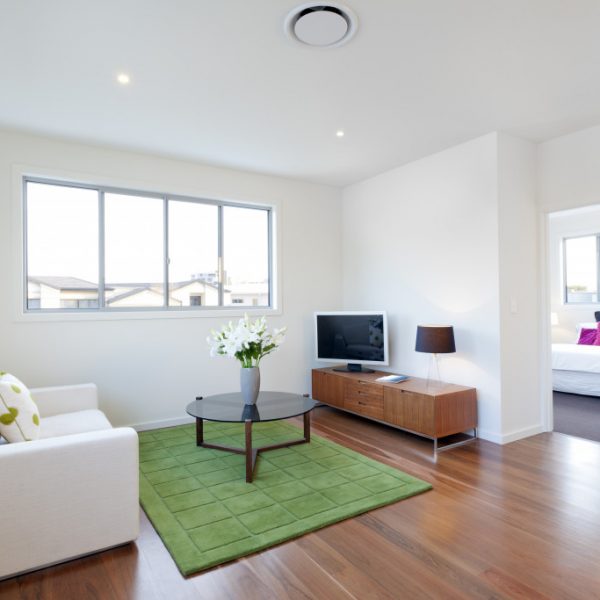 Modern living room with a couch, television, table, and white walls.