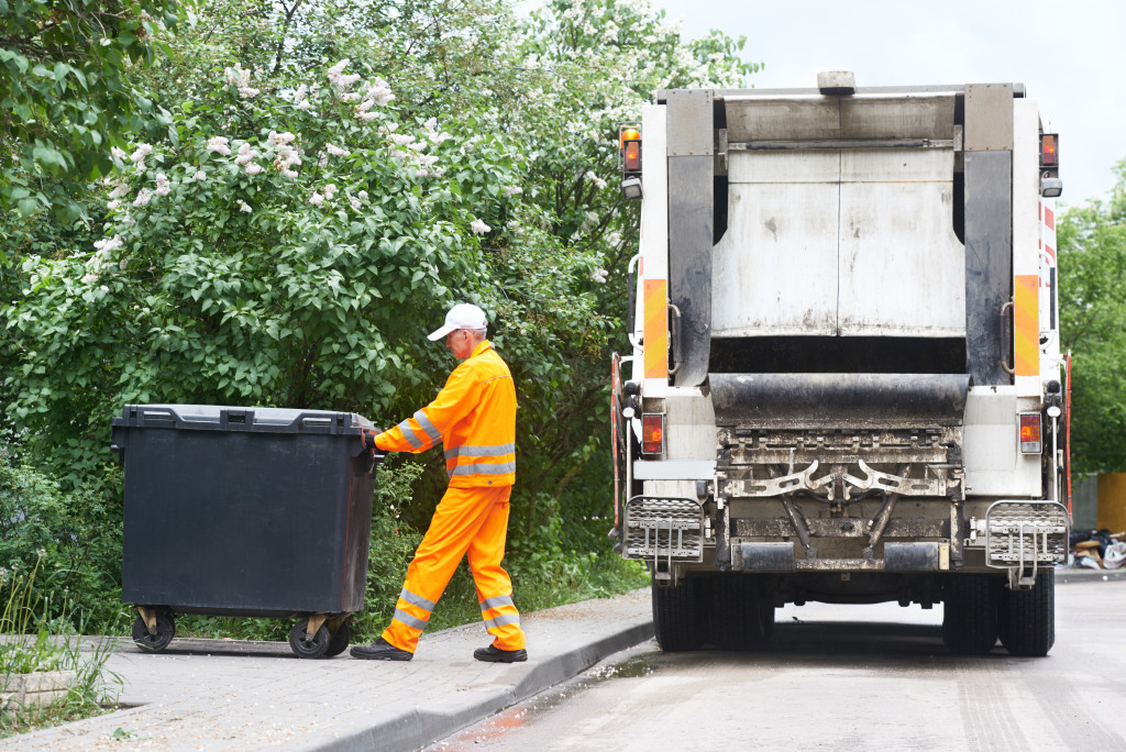 An image of a garbage collector loading waste on a truck